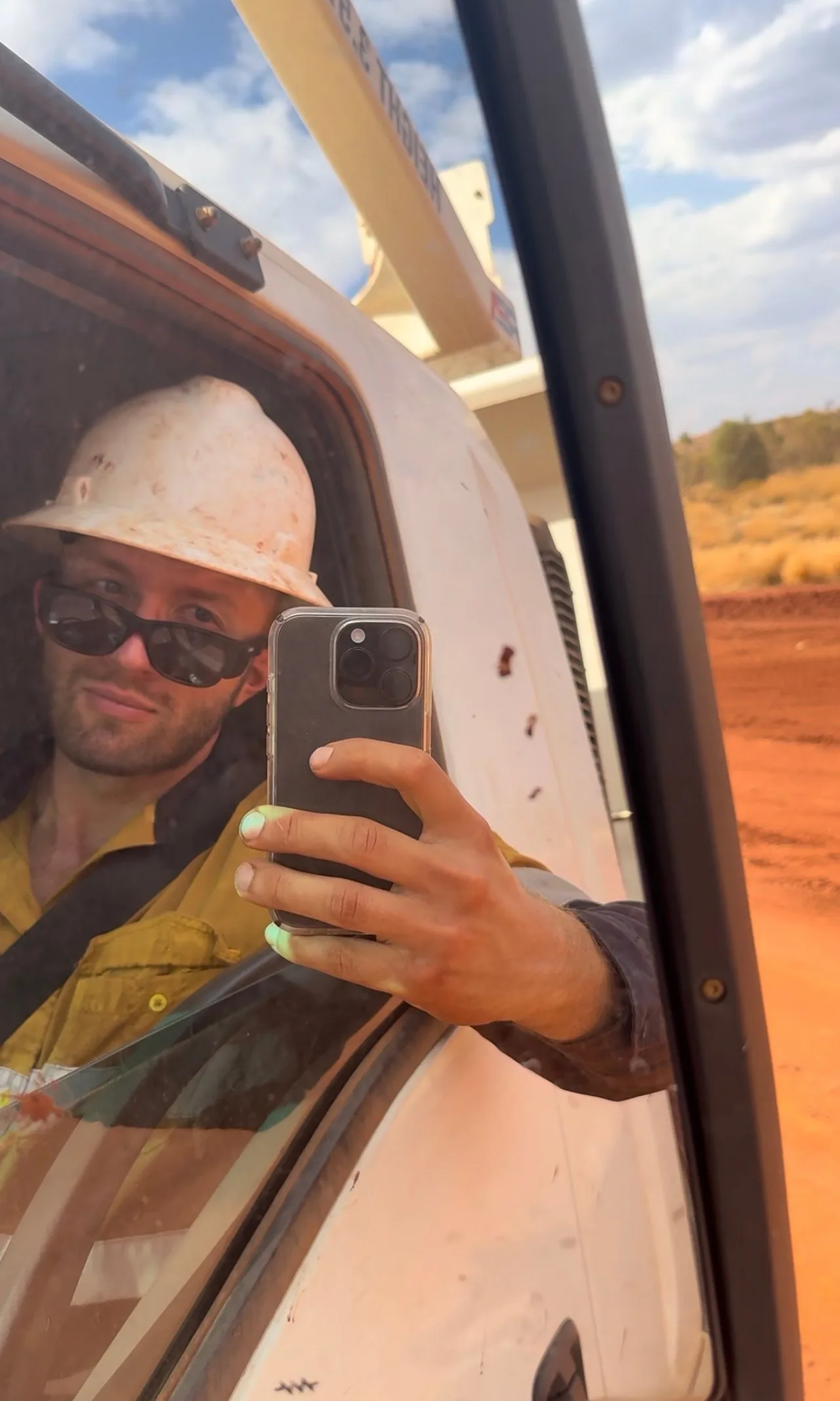 Nico Hein mit Helm und Sonnenbrille am Steuer eines Servicefahrzeugs in der Pilbara, im Hintergrund rote Erde
