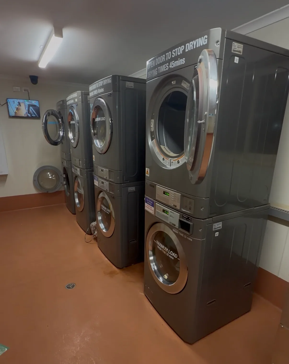 Laundry Room im Camp mit übereinander gestapelten Waschmaschinen und Trocknern, auf den Geräten stehen die Laufzeiten